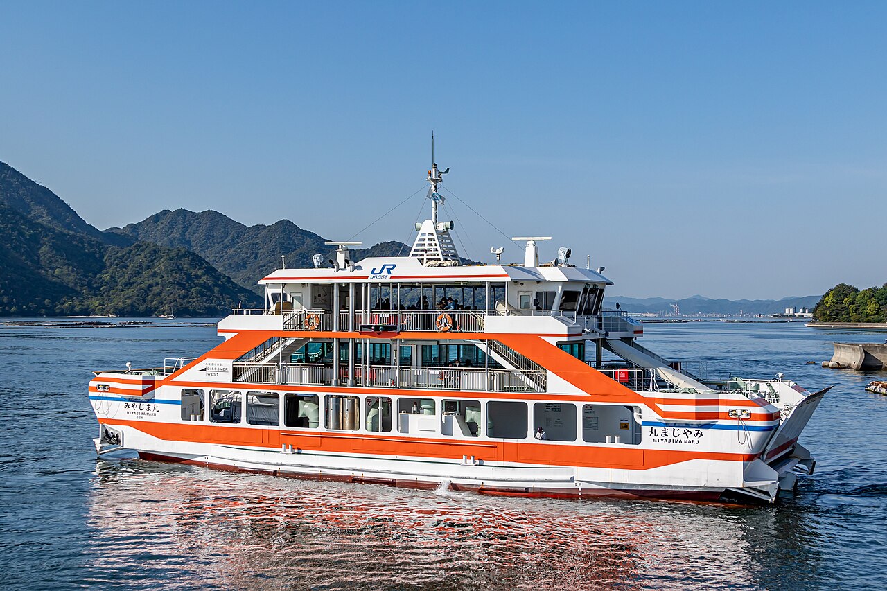 JR Miyajima ferry Miyajima Maru on blue water, with the island hills behind it.